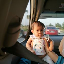 Cropped hands of woman holding baby girl in car