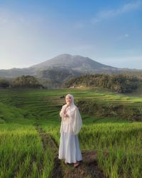 Rear view of woman standing on field against sky