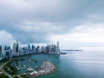 Panoramic view of bay and buildings against sky