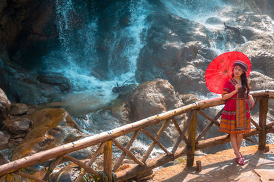 Woman standing on rock against waterfall