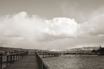 Pier on sea against cloudy sky