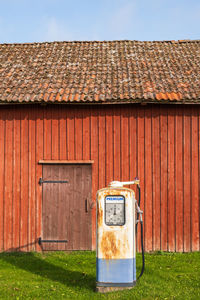 Old petrol pump by a red barn