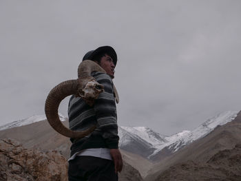 Man standing on snow covered mountain against sky