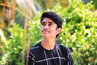 Portrait of young man standing against trees