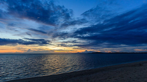 Scenic view of sea against dramatic sky during sunset