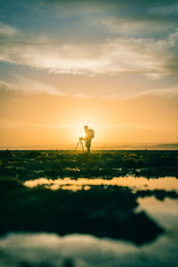 Silhouette man standing on land against sky during sunset