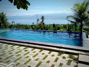 Swimming pool by sea against sky