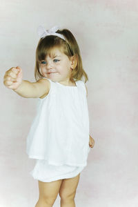 Portrait of cute girl standing against wall