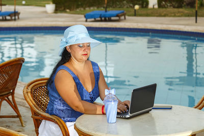 Young woman using mobile phone while sitting on table