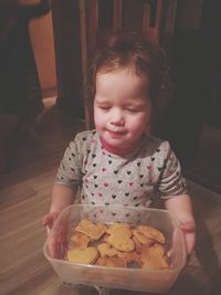 Girl holding cookies in container at home