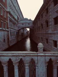 Bridge over canal amidst buildings against sky