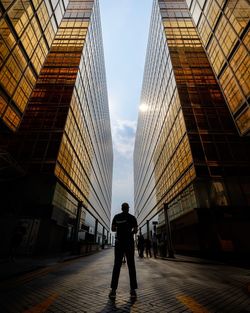 Rear view of man walking on modern office buildings