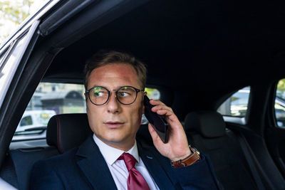 Businessman talking on smart phone sitting in car