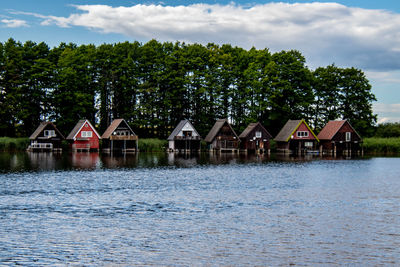 Houses by lake and buildings against sky