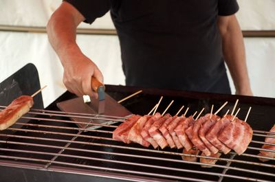 A man cooks skewered meat at a roadside food stand in kyoto, tokyo