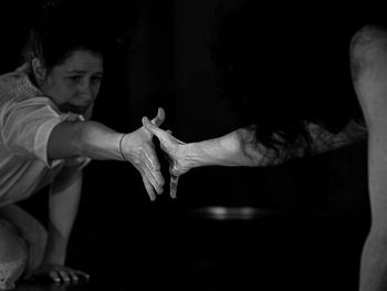 Friends shaking hands against black background