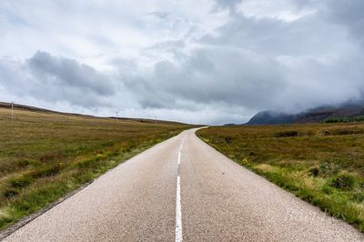 Road amidst field against sky