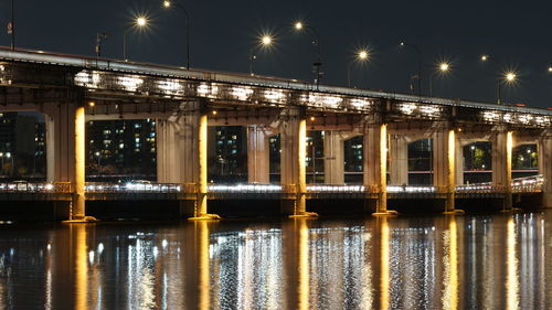 Illuminated bridge over river at night