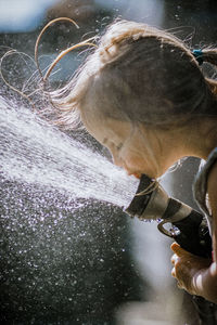 Girl drinking at the hose on a hot summer day