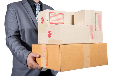 Midsection of man holding box standing against white wall