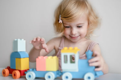 Pretty caucasian 1,2 year old with blond curly hair playing with colourful construction cubes, toy