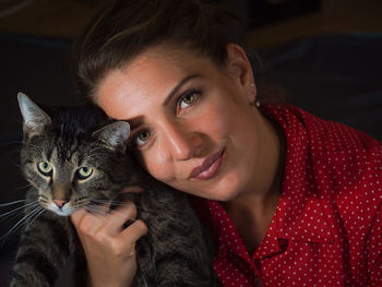 Portrait of smiling young woman with cat at home