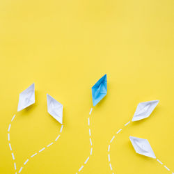 Directly above shot of paper boats against yellow background