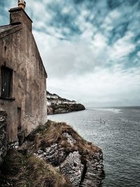 Old building by sea against sky