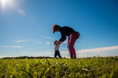 Mother holding hands of daughter while standing on land against sky