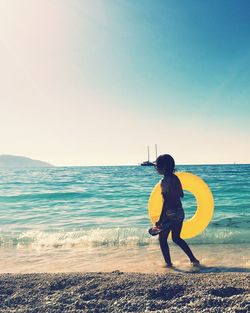 Full length of woman standing on beach against clear sky