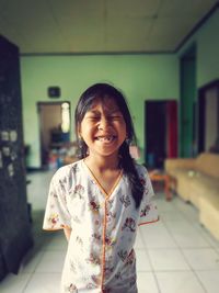 Girl with eyes closed smiling while standing at home