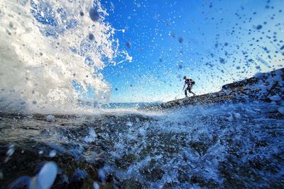 Man splashing water in sea against sky