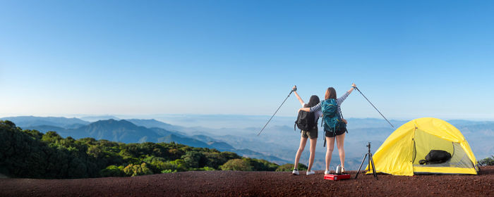 Rear view of people on land against clear blue sky