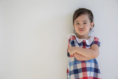 Portrait of cute girl standing against white background