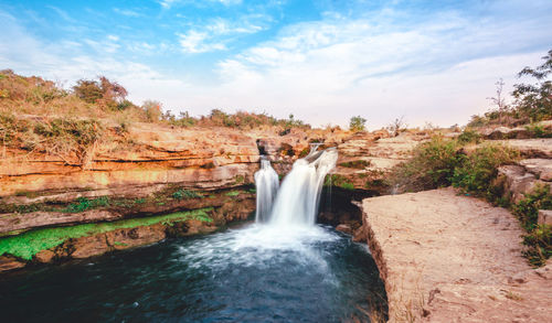 Scenic view of waterfall against sky