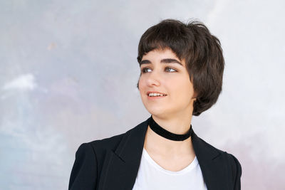 Portrait girl in black jacket with checker around her neck against wall. pretty