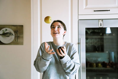 Portrait of a smiling young woman standing in kitchen