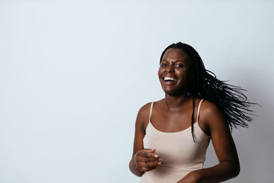 Portrait of laughing young woman against gray background