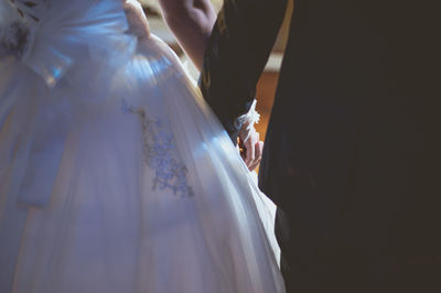 Midsection of bride and groom holding hands during wedding ceremony