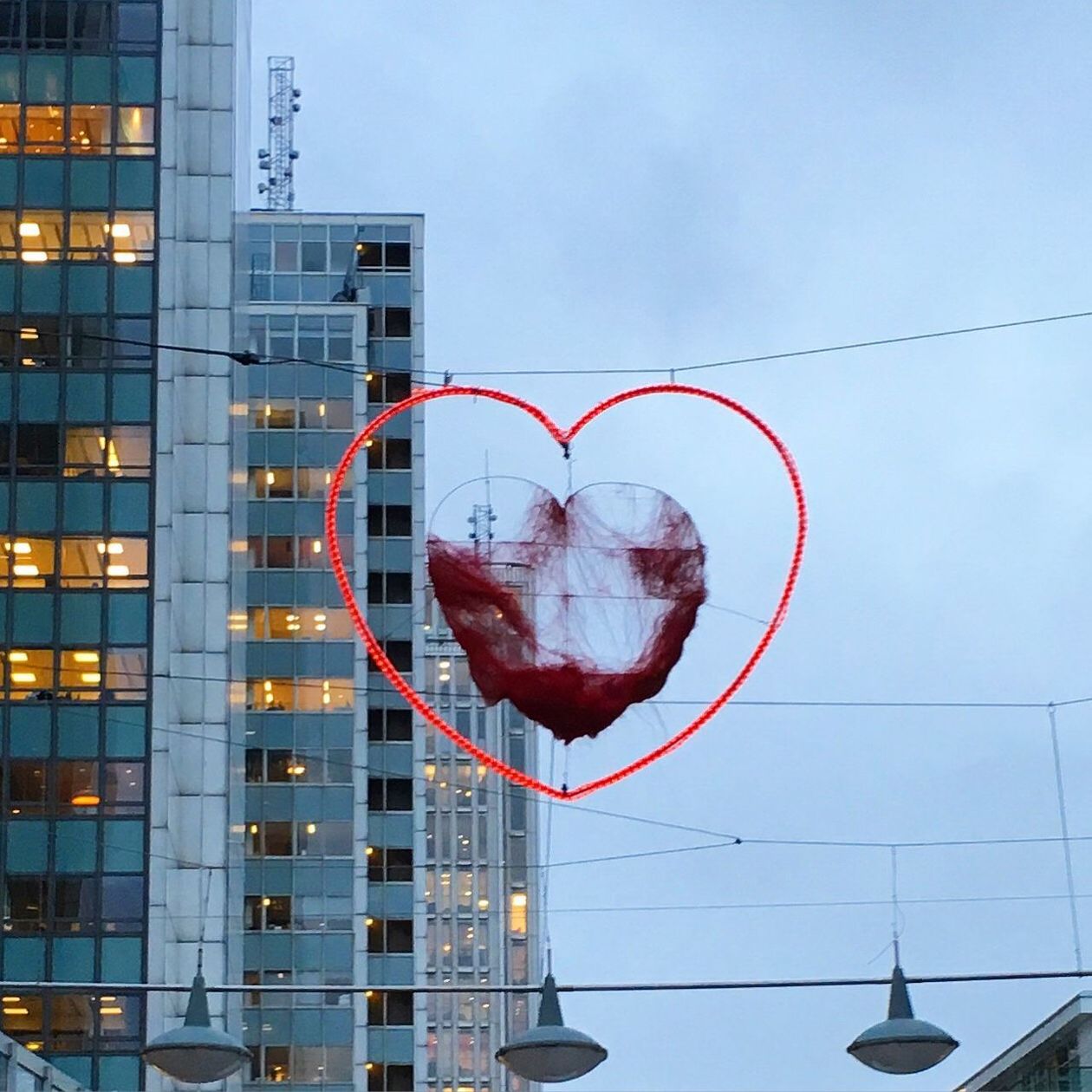 DIGITAL COMPOSITE IMAGE OF HEART SHAPE ON GLASS BUILDING AGAINST SKY