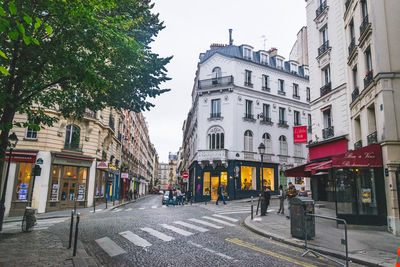 Road by buildings in city against sky