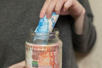 Midsection of woman removing paper currency from jar