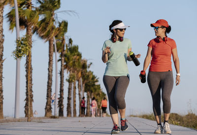 Women walking on footpath against sky