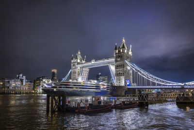 Illuminated bridge over river against sky at night