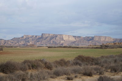Scenic view of field by mountain against sky