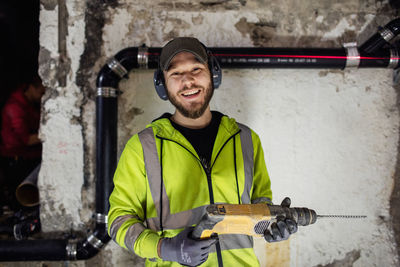 Portrait of manual worker with drill machine standing in basement