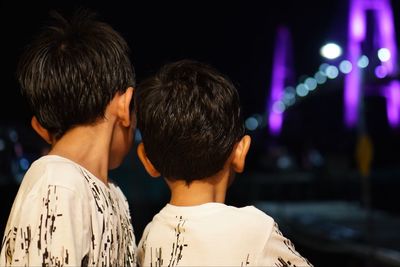 Rear view of boys against illuminated street light at night