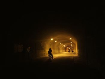 Silhouette of people walking in tunnel