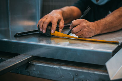 Unrecognizable person working in a workshop cutting metal, sparks are seen