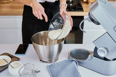 Woman cooking at kitchen and using kitchen machine